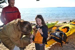 teen helping sister get ready to kayak